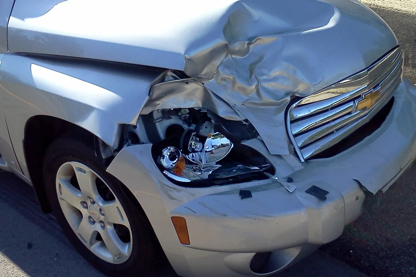Sample photo: a silver Chevrolet HHR with the hood crumpled, the headlight smashed and the bumper pushed in.